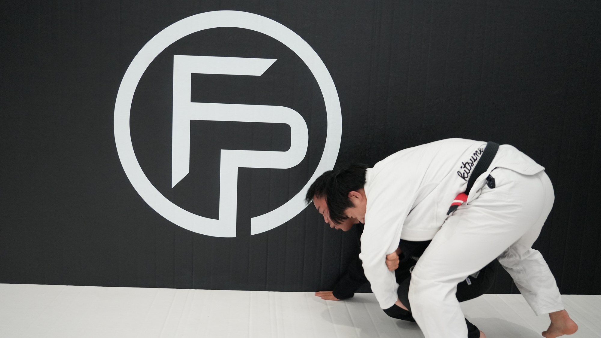 A coach shooting a takedown on the mats at First Page Grappling